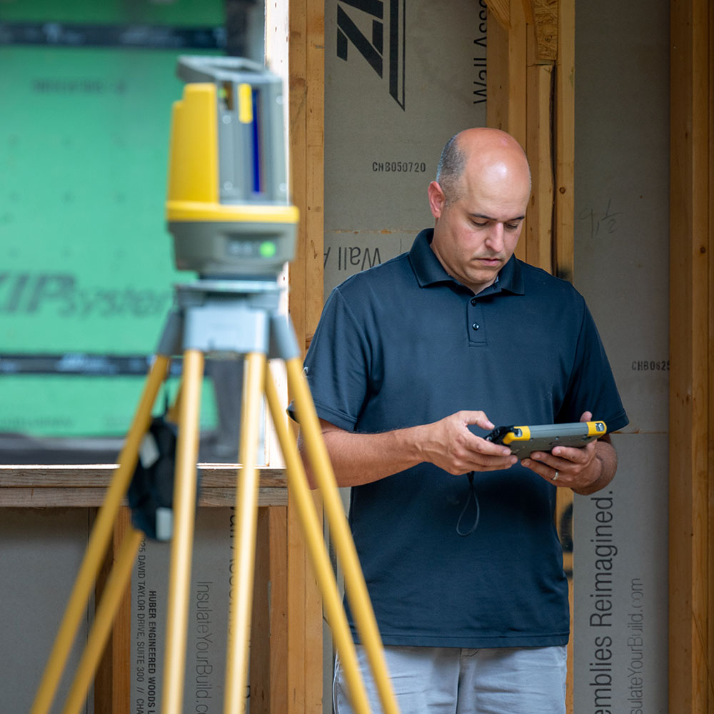 Worker using a field controller to operate an LN-150 robotic total station